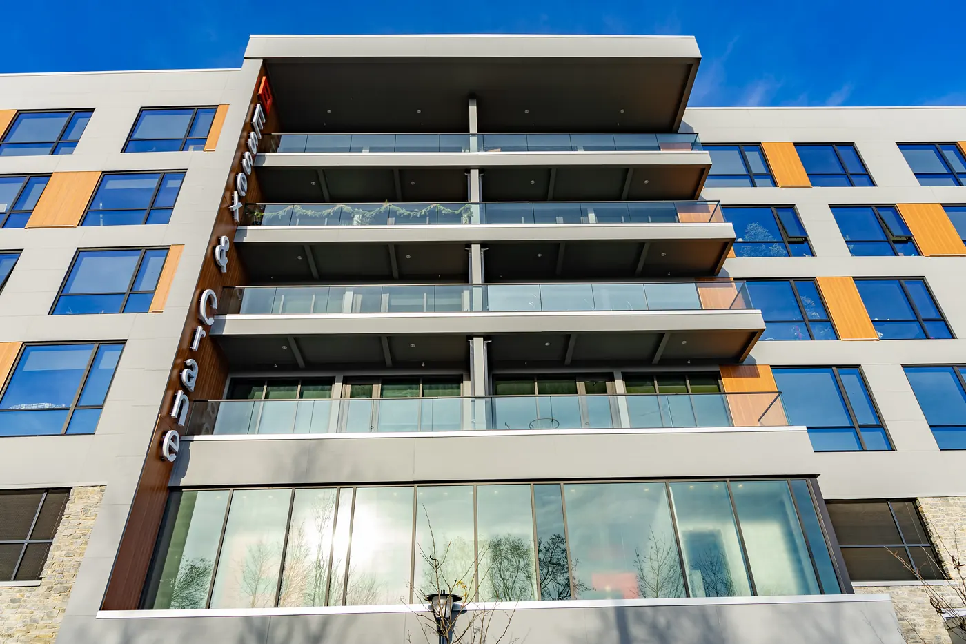 Stacked balconies with frameless glass guards above a glazed ground floor at Essex + Crane in Orange, New Jersey